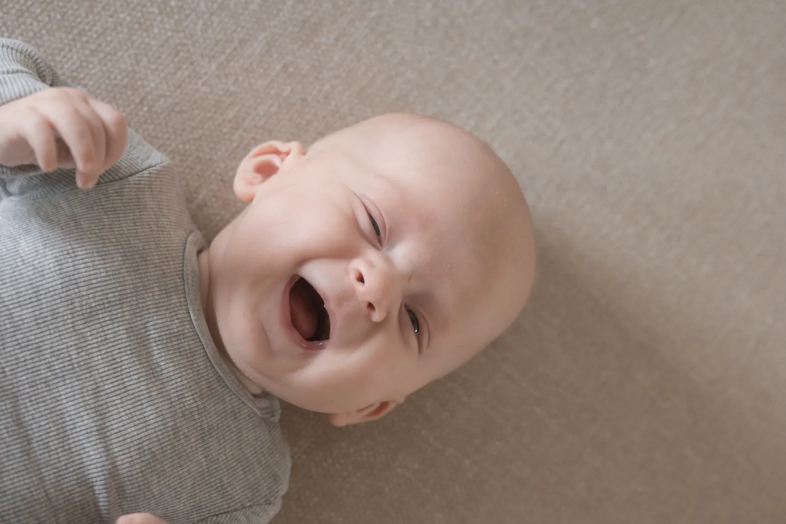 Baby griner på et tæppe